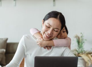 Mother working on laptop with daughter around her