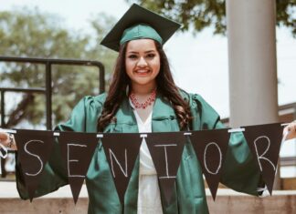 High school graduate holding a "senior" banner
