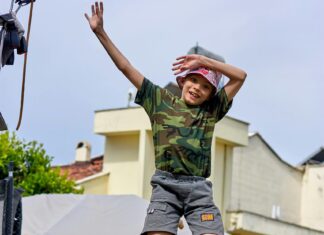 A Kid in Camouflage T-shirt Jumping on a Trampoline