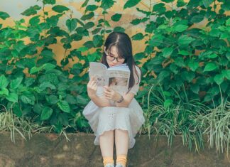 Child reading a book on an overgrown street curb
