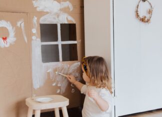 Child painting a cardboard house