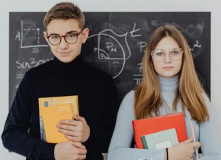Two Teenagers with Books Against a Blackboard