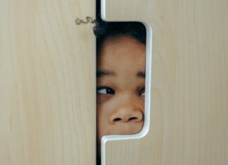 Playful black little girl hiding in closet