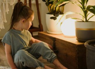 Little girl contemplating shiny lamp in living room