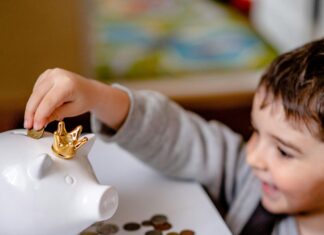 Boy in Gray Long Sleeve Shirt Putting Coins in a Piggy Bank