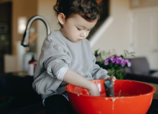 An Adorable Child Sitting On Counter Top With A Mixing Bowl