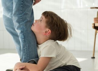 Boy Sitting on the Floor while Hugging a Person's Leg