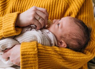 Woman in Yellow Knit Sweater Carrying Baby