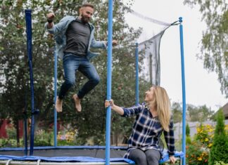 A Woman Looking at a Man Jumping on a Trampoline