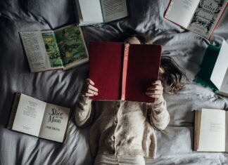 Child laying on bed and reading a book