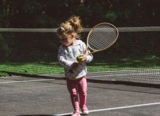 Little girl on a tennis court with a tennis racket
