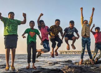 Boy Wearing Green Crew-neck Shirt Jumping from Black Stone on Seashore