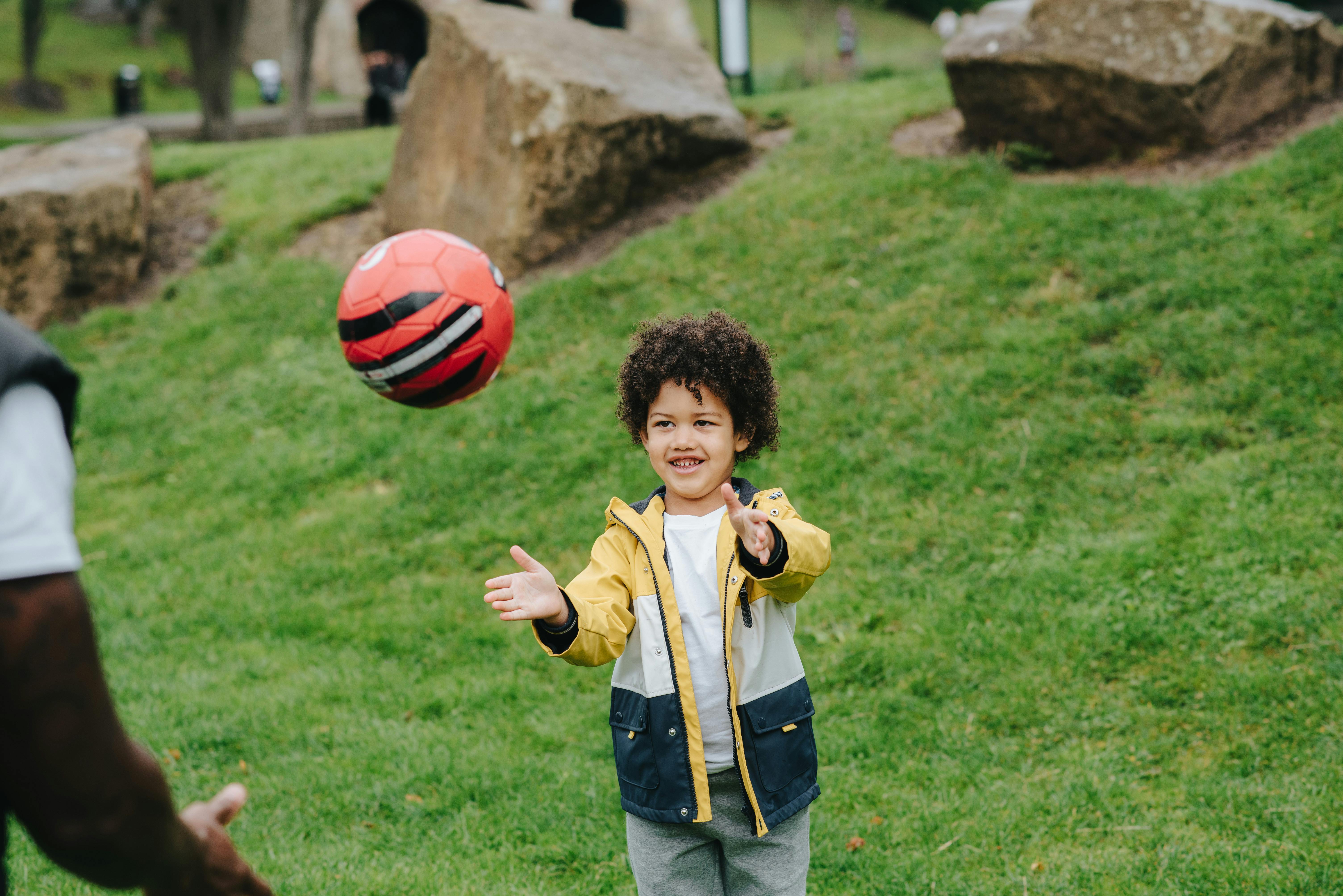 Cheerful black boy playing with ball