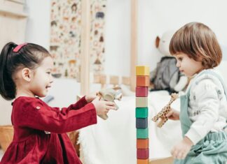 Boy in White Long Sleeve Shirt and Green Pants Sitting on Floor Beside girl in Red