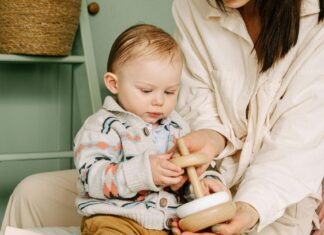 Baby Boy Playing with Wooden Toy Beside a Woman