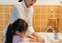 Mom teaching little daughter to wash hands properly