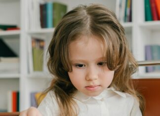 Photograph of a Child with Brown Hair Arranging Colored Pencils