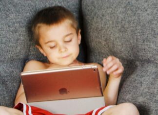 Children lying on sofa and using gadgets
