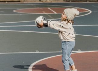 Cheerful girl playing ball on sport ground