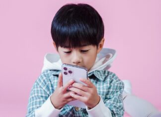 Ethnic boy checking messages on phone in room