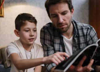 Photo of Man and a Boy Reading Magazine Together