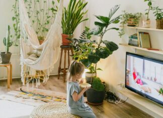 Unrecognizable girl eating and watching TV in living room