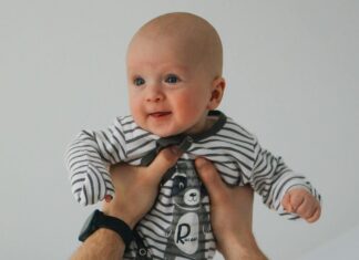Man in White T-Shirt Carrying Baby in Black and White Stripe Onesie